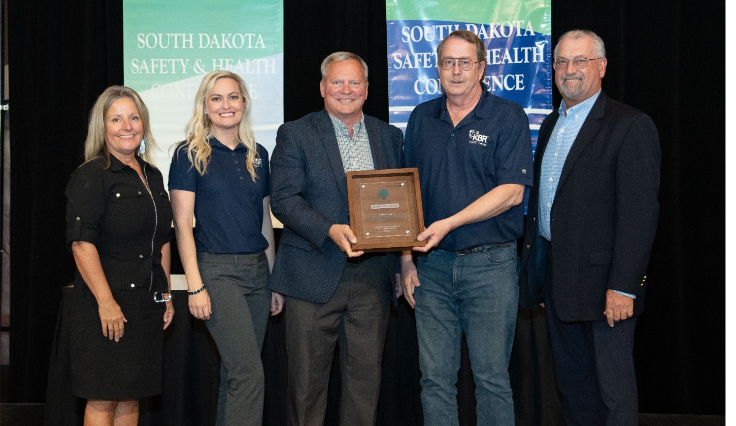 The KBR/TSSC team accepts the 2021 South Dakota Workplace Safety Council - Award of Honor at the South Dakota Safety Conference luncheon event on Oct. 5, 2022. Featured from left to right: Janie Ritter, Executive Director of SD Safety Council; Bobbi Britt - KBR/TSSC Human Resources; Douglas Jaton - KBR/TSSC Program Manager; Brent Nelson, KBR/TSSC Zero Harm Safety Manager; and James Carnes, KBR/S&S Corporate Zero Harm Safety Manager.