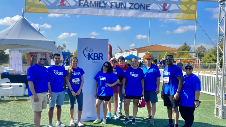 KBR employees gathered under a Family Fun Zone sign
